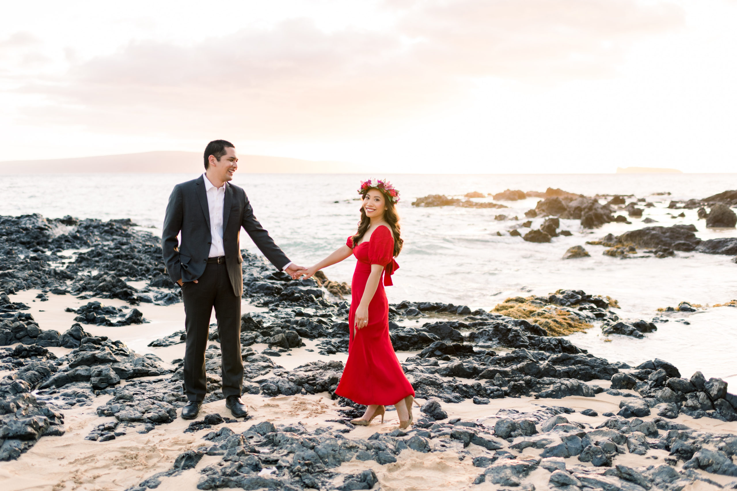 Honeymoon Couple in Maui holding hands while standing in sand and rocks during sunset.