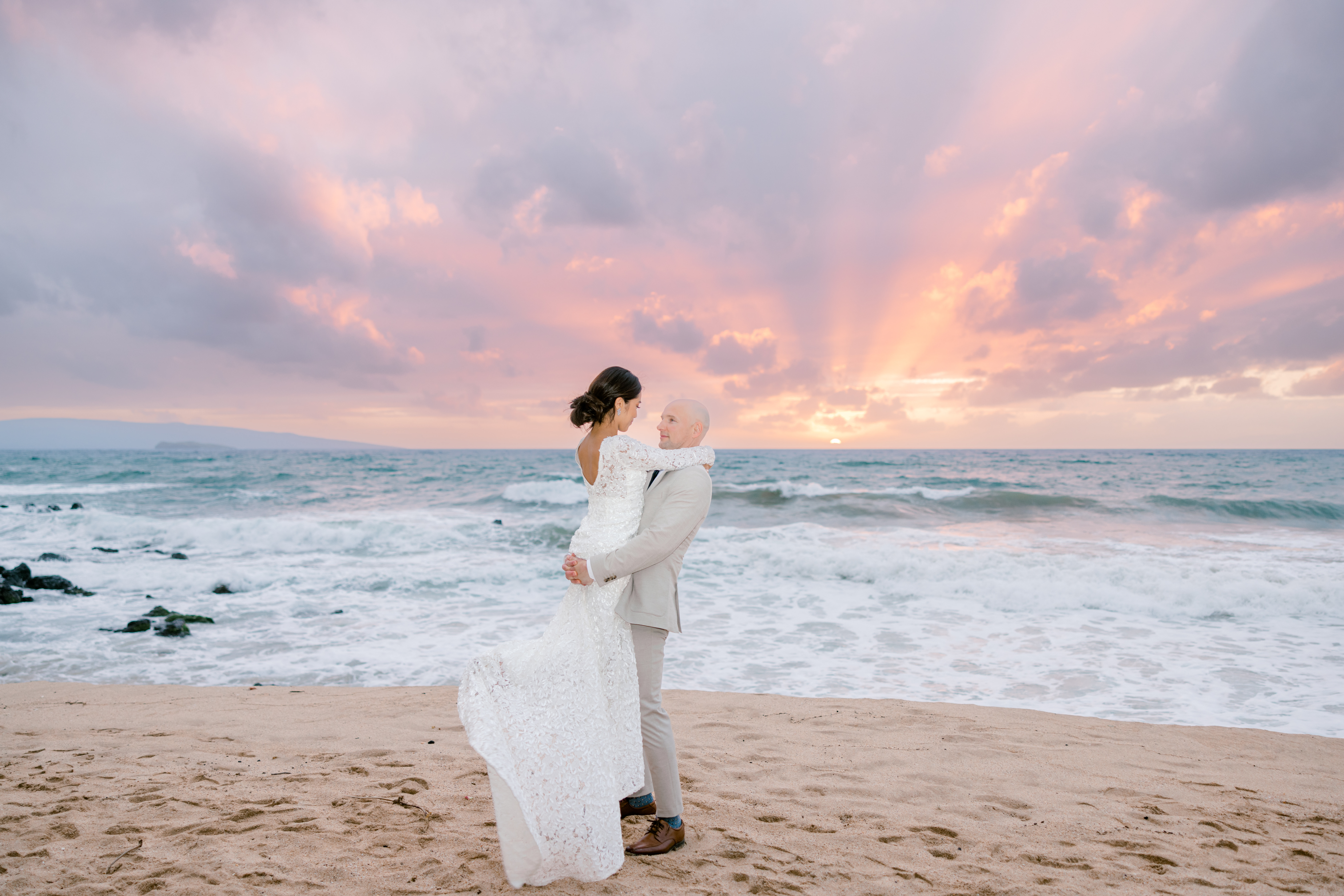 Groom lifting bride while at White Rock Beach in Maui, HI.