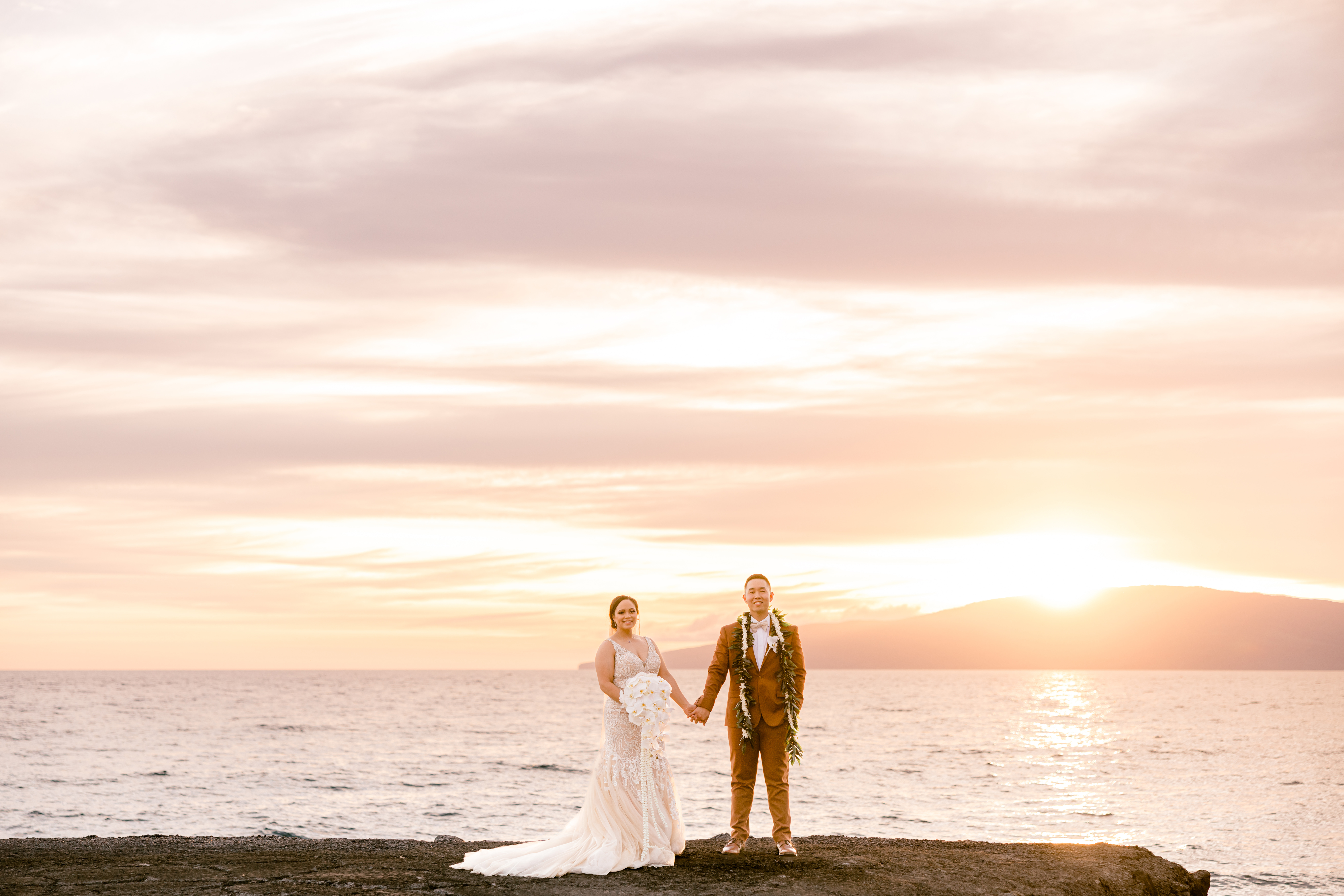 Newlyweds man and woman standing side by side holding hands during their photography session at Maui Camp Olowalu .