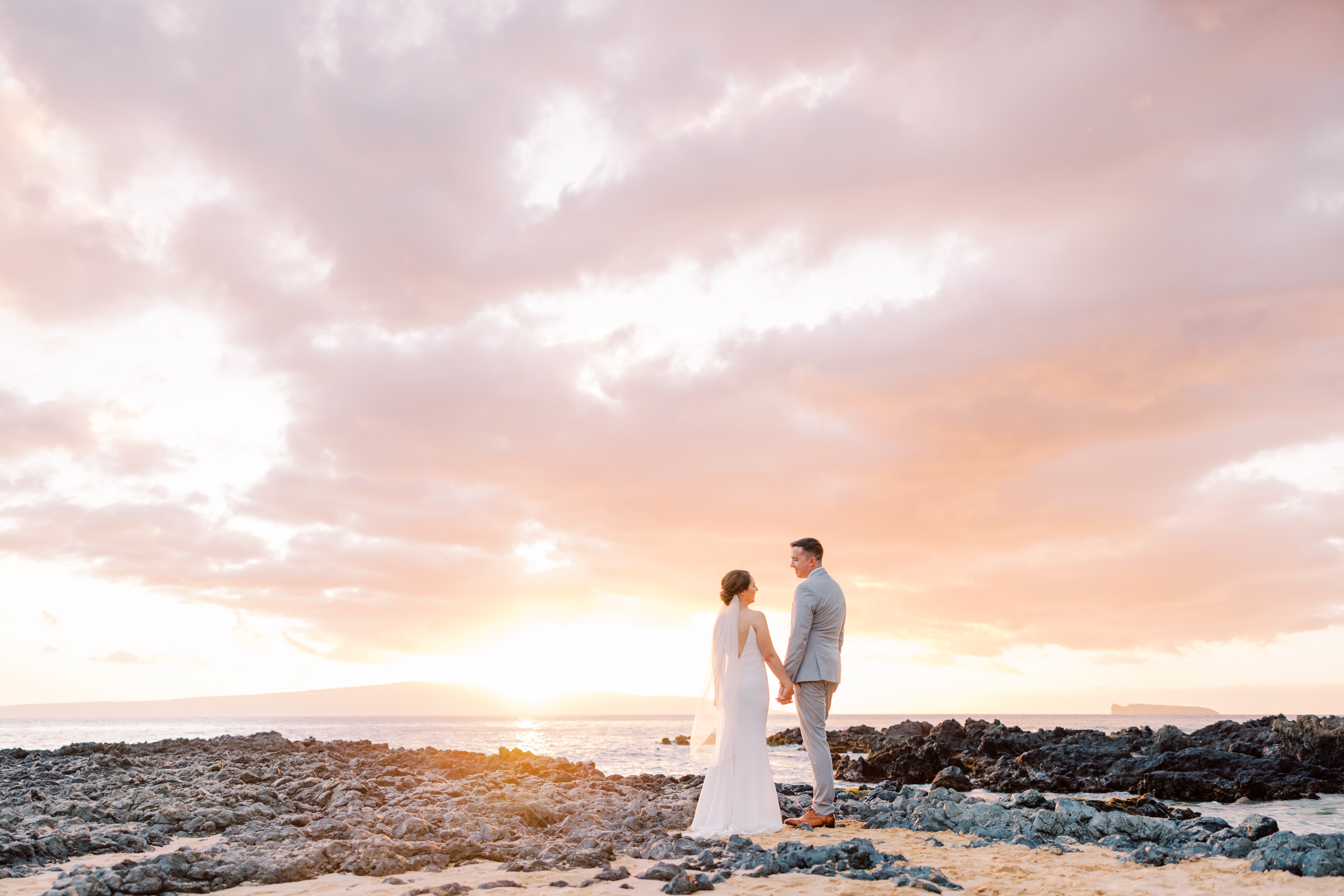 man and woman couple from Canada standing on a beach holding hands during sunset in Maui