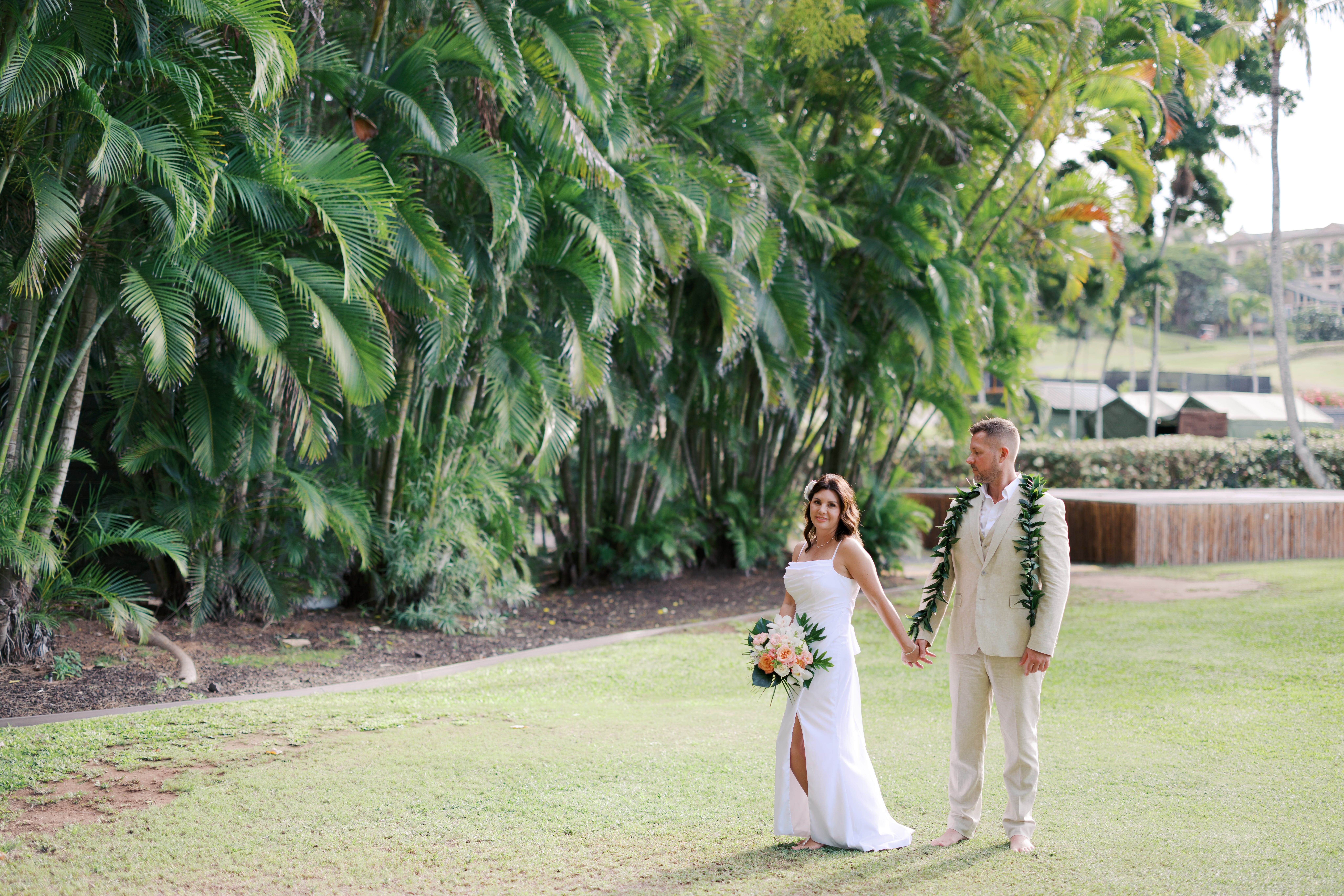 Kapalua wedding photographer captured bride and groom holding hands with palm trees in the backdrop